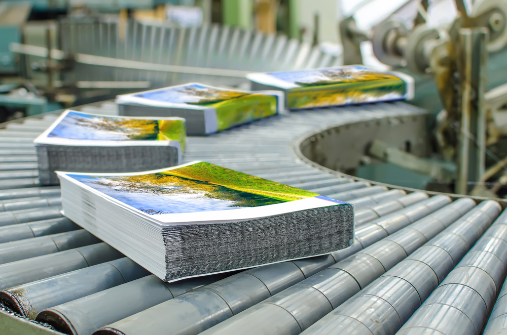 Same day print and marketing courier services by Transol Sameday - freshly printed magazines and booklets on a conveyor belt in an industrial printing facility